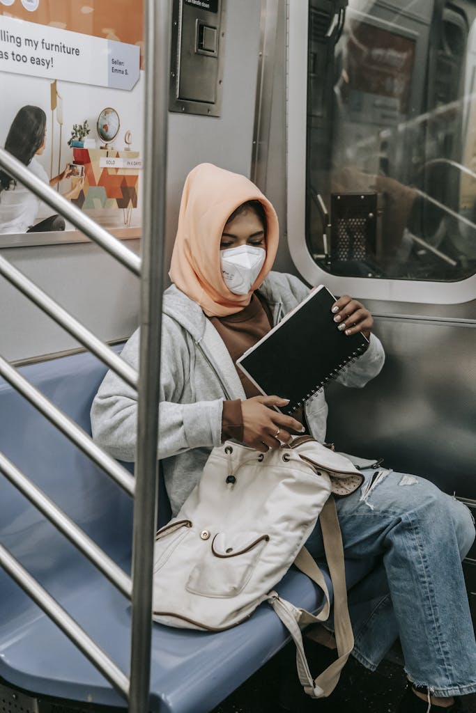 Muslim woman with notepad in underground train